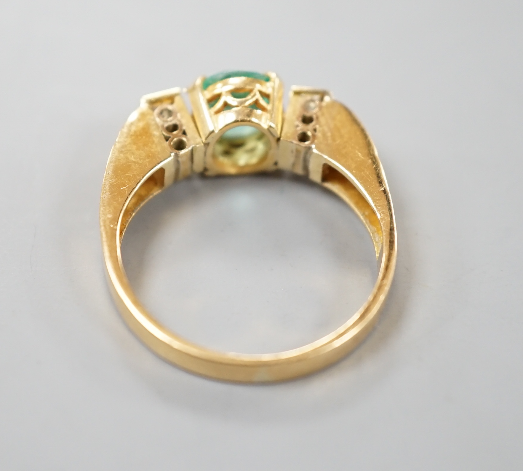 A modern yellow metal, round cut emerald and two stone baguette cut diamond set dress ring, with pierced shoulders, size Q/R, gross 5.5 grams.